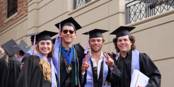 Four students posing in their academic regalia at commencement