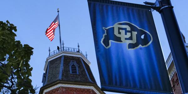 Old Main building and a CU flag