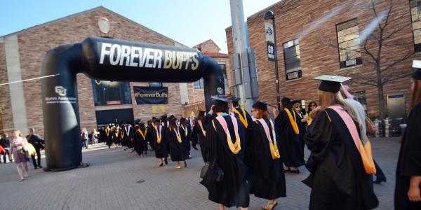 Graduates walking under Forever Buffs inflatable arch